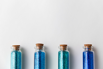 Image showing blue glitters in bottles over white background