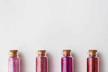 Image showing red glitters in bottles over white background