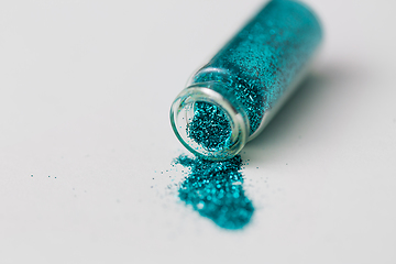 Image showing blue glitters poured from small glass bottle