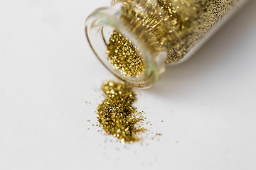 Image showing golden glitters poured from small glass bottle