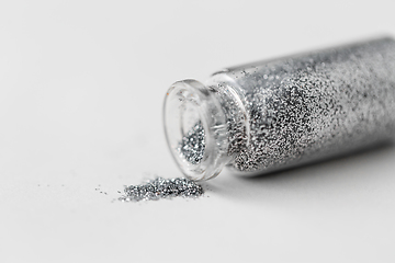 Image showing silver glitters poured from small glass bottle