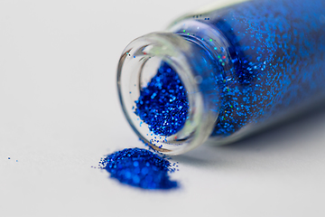 Image showing blue glitters poured from small glass bottle