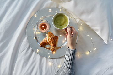 Image showing hand of woman drinking coffee with croissant