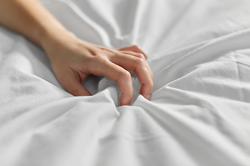 Image showing hand of woman squeezing white bed sheet