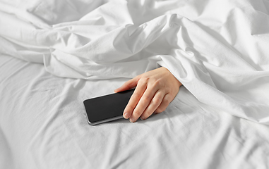 Image showing hand of woman lying in bed with smartphone