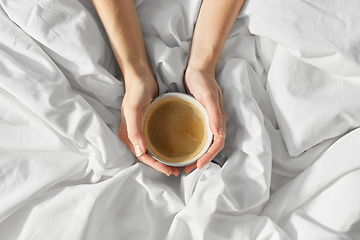 Image showing hands of woman with cup of coffee in bed