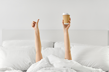 Image showing woman with coffee lying in bed showing thumbs up