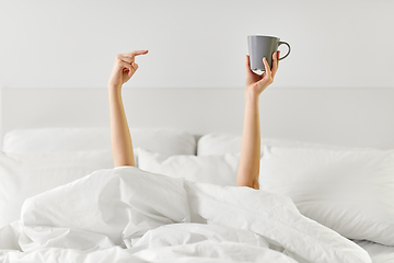 Image showing woman with cup of coffee lying in bed