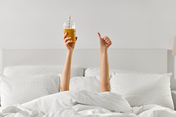 Image showing hands of woman lying in bed with cup of juice