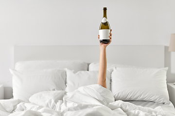 Image showing hand of woman lying in bed with champagne