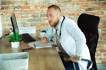 Image showing Caucasian doctor consulting for patient, explaining recipe for drug, working in cabinet