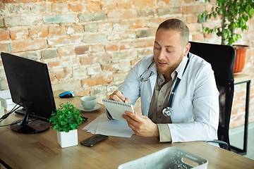 Image showing Caucasian doctor consulting for patient, explaining recipe for drug, working in cabinet