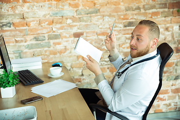 Image showing Caucasian doctor consulting for patient, explaining recipe for drug, working in cabinet