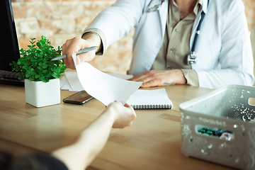 Image showing Close up of caucasian doctor consulting for patient, explaining recipe for drug, working in cabinet