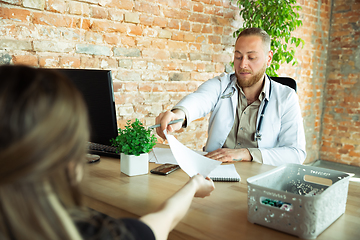 Image showing Caucasian doctor consulting for patient, explaining recipe for drug, working in cabinet