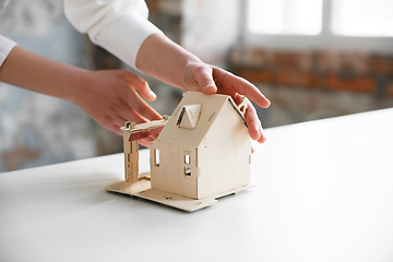 Image showing Close up of future house model. Female estate agent showing new home to a young man after a discussion on house plans, moving, new home concept