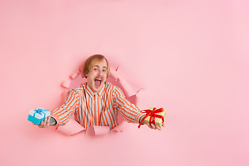 Image showing Cheerful young man poses in torn coral paper hole background, emotional and expressive