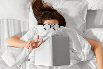 Image showing woman lying in bed with book and glasses