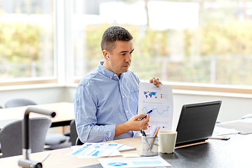 Image showing man in earphones with laptop working at home