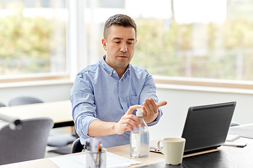 Image showing man using hand sanitizer at home office