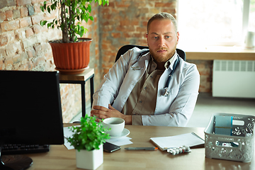 Image showing Caucasian doctor consulting for patient, explaining recipe for drug, working in cabinet