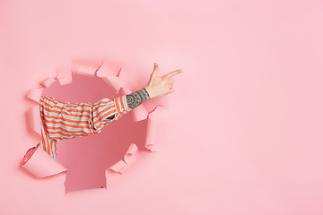 Image showing Male hand pointing, showing in torn coral paper hole background, copyspace