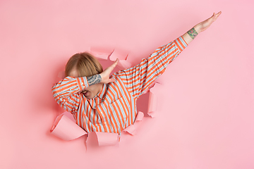 Image showing Cheerful young man poses in torn coral paper hole background, emotional and expressive