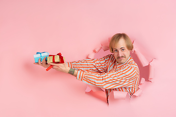 Image showing Cheerful young man poses in torn coral paper hole background, emotional and expressive