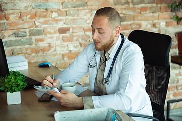 Image showing Caucasian doctor consulting for patient, explaining recipe for drug, working in cabinet