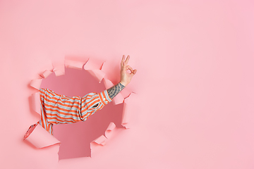 Image showing Male hand pointing, showing nice in torn coral paper hole background, copyspace