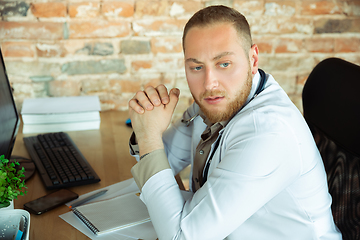 Image showing Caucasian doctor resting after consulting for patient, working in cabinet