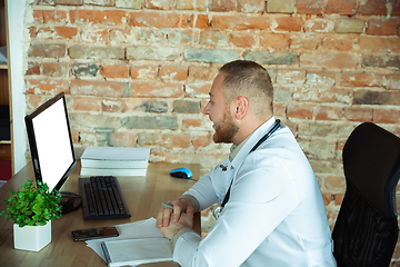 Image showing Caucasian doctor consulting for patient, explaining recipe for drug, working in cabinet