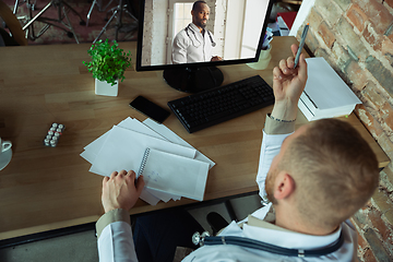 Image showing Caucasian doctor has online conference with colleague, consulting, working in cabinet