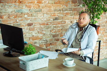 Image showing Caucasian doctor consulting for patient, explaining recipe for drug, working in cabinet