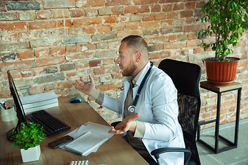 Image showing Caucasian doctor consulting for patient, explaining recipe for drug, working in cabinet