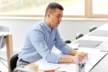 Image showing architect with blueprint working at home office