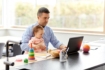 Image showing father with baby working on laptop at home office