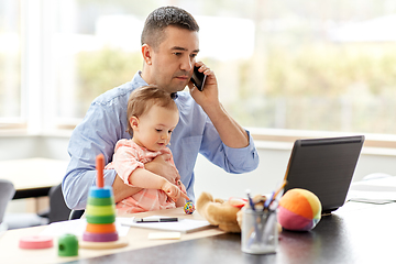 Image showing father with baby calling on phone at home office