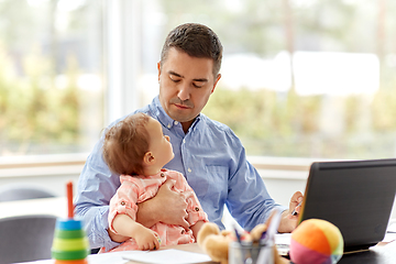 Image showing father with baby working on laptop at home office