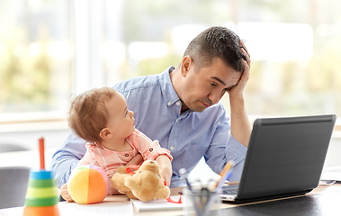 Image showing father with baby working on laptop at home office