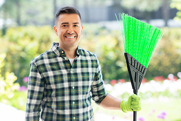 Image showing happy middle-aged man with broom at garden