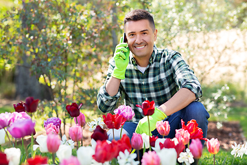 Image showing man with flowers calling on smartphone at garden