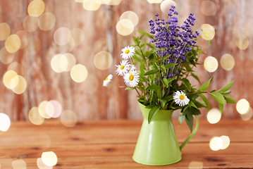 Image showing bunch of herbs and flowers in green jug on table