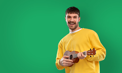 Image showing happy man playing ukulele guitar over green