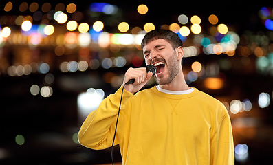 Image showing man with microphone singing over night city lights