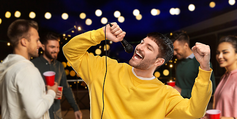 Image showing man with microphone singing at night rooftop party