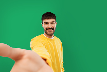 Image showing happy young man in yellow sweatshirt making selfie