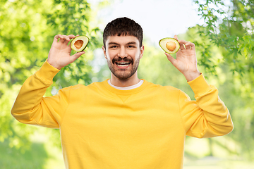 Image showing happy young man in yellow sweatshirt with avocado