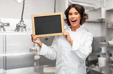 Image showing smiling female chef holding black chalkboard