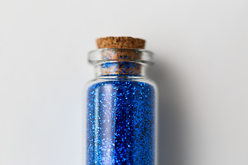 Image showing blue glitters in bottle over white background